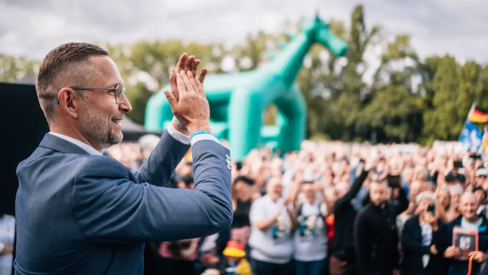 Daniel Wald applaudiert von der Bühne aus dem dicht gedrängten Publikum; im Hintergrund eine große grüne Hüpfburg in Pferdeform.