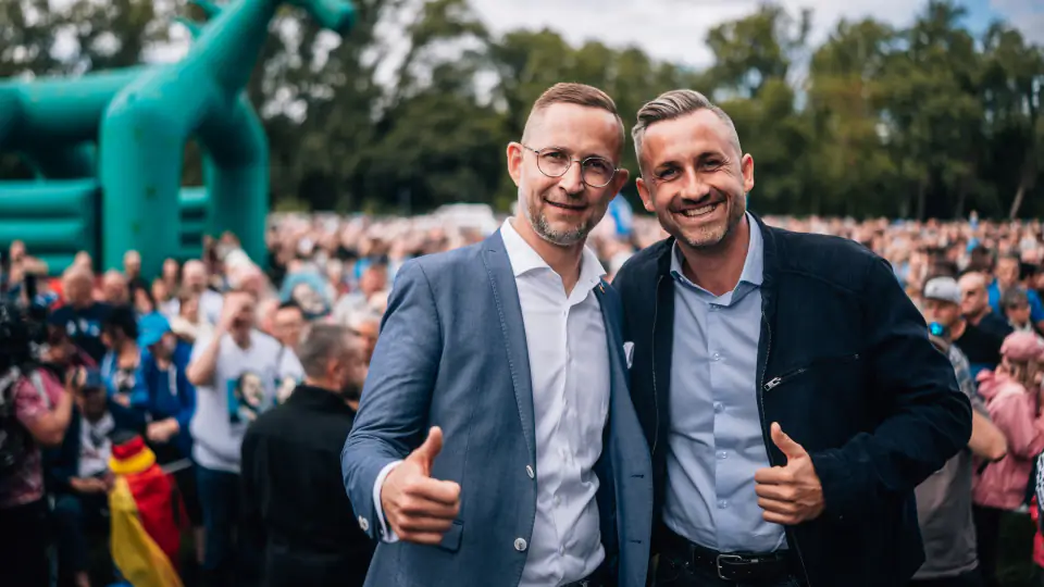 Daniel Wald und Ulrich Siegmund stehen nebeneinander vor dem Publikum und zeigen beide den Daumen nach oben.