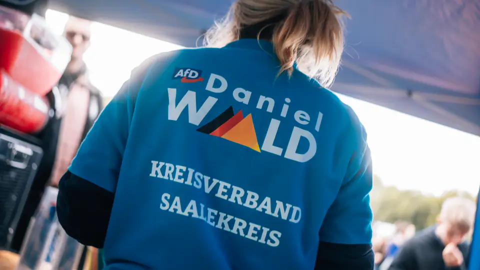Rückenansicht einer Helferin in einem blauen Sweatshirt mit dem Aufdruck „AfD Daniel Wald, Kreisverband Saalekreis".